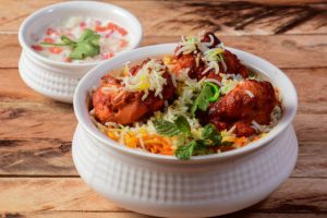 Chicken Tikka Biryani made of Basmati rice cooked with masala spices, served with yogurt, selective focus